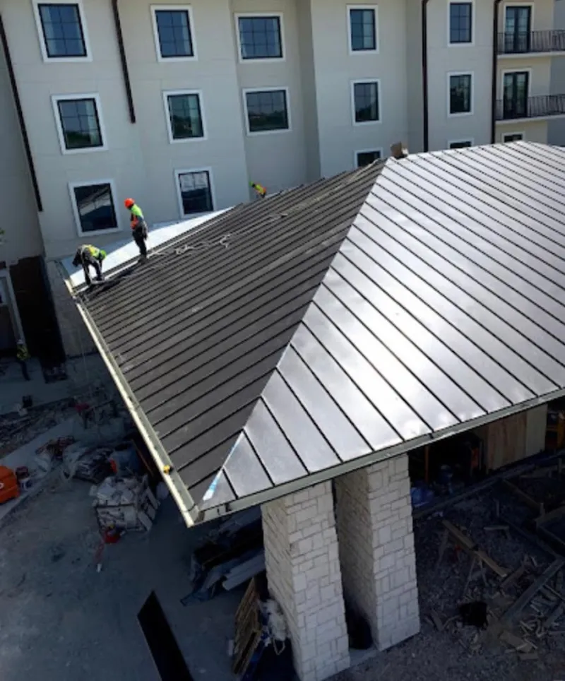 Crew installing standing seam metal roof panels on a commercial project in Darby